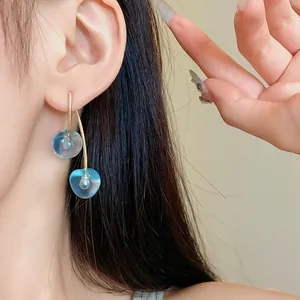 Detail view of stylish blue translucent resin cherry drop earrings on model's ear