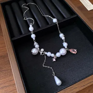 Detail of elegant silver necklace with white pearls and pink rhinestone teardrop tassel