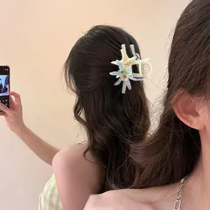 Detail of a sweet starfish and flower hair claw clip on brunette wavy hair.
