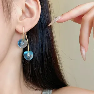 Detailed close-up showing elegant blue translucent cherry resin earrings on a model's ear