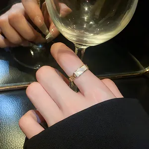 Elegant golden open ring with white shell inlay worn on index finger in luxury setting