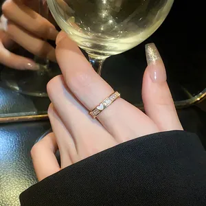 Close-up of a elegant golden heart ring with sparkling zircons worn on index finger.