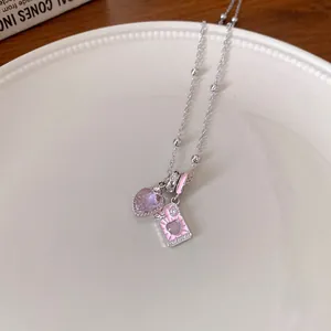 Close-up of a silver necklace featuring lavender heart stone and pink enamel charms