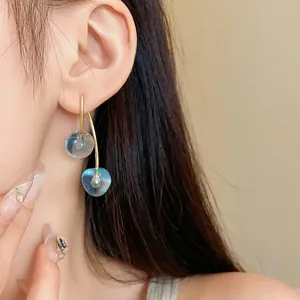 Close-up detail of stylish transparent blue cherry resin earrings with silver needles.