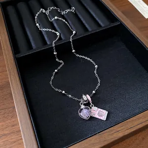Close-up of heart-shaped purple stone and pink enamel card pendant on silver chain.