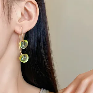 Close-up detail of translucent green resin cherry drop earrings with gold-tone stems