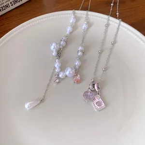 Detail view of elegant pearl necklace with pink waterdrop gem and heart pendant necklace