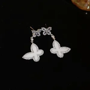 Detailed close-up of butterfly drop earrings featuring shimmering crystals and white inlay