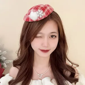 Dettaglio di un festoso fascinator natalizio a quadri rossi con fiocco di neve e pompon