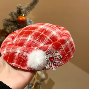 Dettaglio di un fermaglio per capelli natalizio a quadri rossi con pompon di pelliccia.