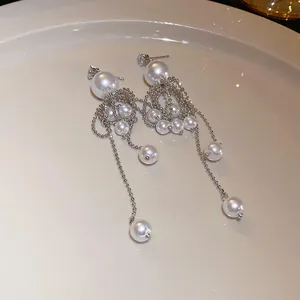 Detailed view of elegant long dangle earrings with white pearls and silver bead chains.
