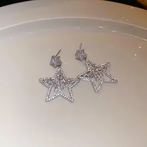 Detailed view of silver star-shaped drop earrings with sparkling rhinestone inlay