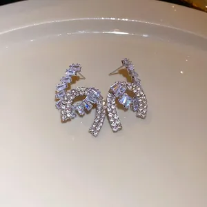Close-up detail of silver-tone bow-knot earrings encrusted with sparkling cubic zirconia