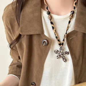 Detailed view of a leopard print flower necklace with wooden beads and fabric cord.