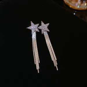 Close-up of silver-tone star earrings with sparkling rhinestones and long fringe tassels