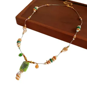 Vintage bohemian beaded necklace with green rectangular pendant on wooden background