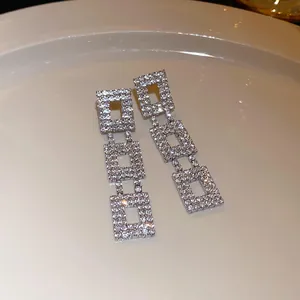Detailed view of silver-tone triple square drop earrings encrusted with sparkling rhinestones