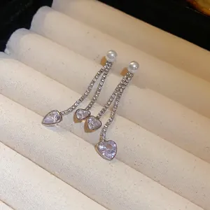 Detailed close-up of elegant silver dangling heart earrings with pearls and rhinestones