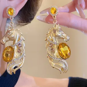 Detail view of vintage gold horse head earrings with amber crystals and pave stones.