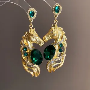 Detailed macro view of vintage gold-tone horse earrings with emerald green crystal accents