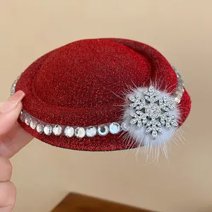 Primo piano di un fermaglio per capelli a forma di mini cappello rosso glitterato con fiocco.
