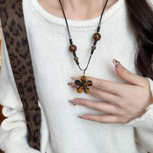 Detail view of a leopard print flower pendant necklace in Maillard vintage style