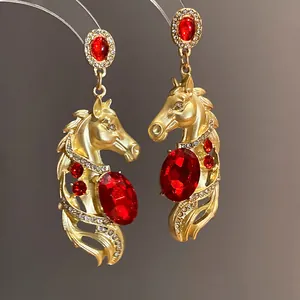 Close-up detail of vintage gold horse-shaped earrings with sparkling red crystals.