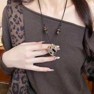 Detailed view of retro leopard print heart necklace with leather cord and wooden beads style.