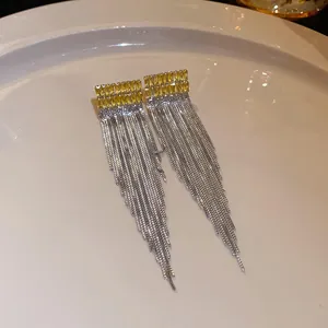 Close-up of silver chain tassel earrings featuring elegant yellow baguette stones.