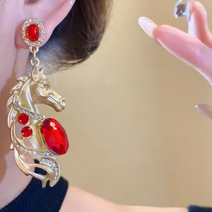 Close-up detail of a luxury vintage horse head earring with large red crystals and gold finish