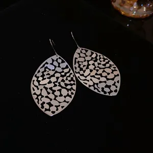 Detailed macro shot of elegant silver cutout filigree earrings on a black velvet background