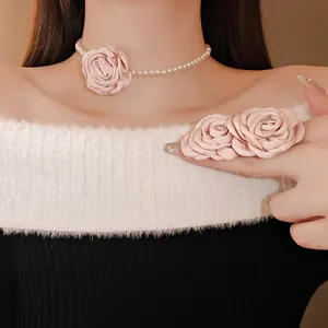 Detailansicht einer französischen Perlenkette mit rosa Stoffrose an einem Modell.