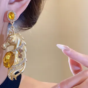 Close-up of vintage golden horse dangle earrings with yellow crystals and pavé diamonds.