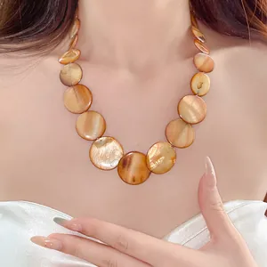 Close-up of Bohemian necklace with amber iridescent round discs on model's neck