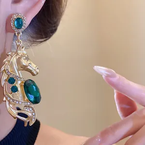 Close-up of vintage horse head earrings with green gemstones and sparkling crystals