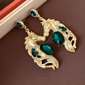 Close-up detail of vintage gold horse head earrings with emerald green gemstones