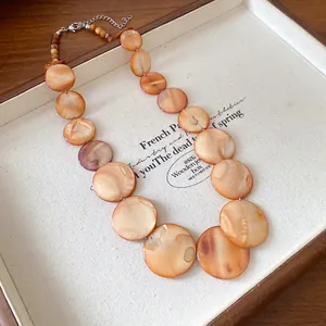 Detail of Bohemian irregular round orange shell necklace with lustrous finish