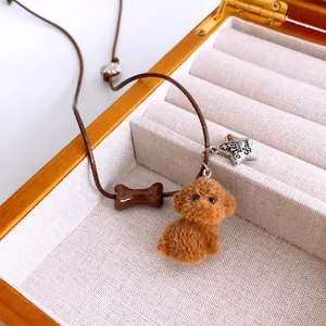 Close-up of brown cord necklace with furry poodle, bone charm and silver Love star tag.
