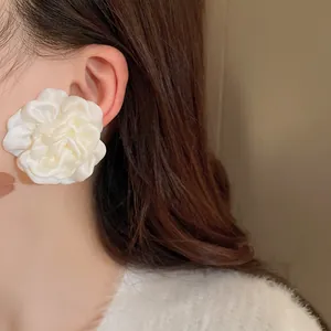 Nahaufnahme eines eleganten weißen Stoffblumen-Ohrrings im französischen Retro-Stil