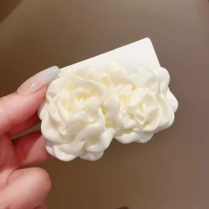 Nahaufnahme von eleganten cremefarbenen Stoffrosen-Haarspangen mit Satin-Blütenblättern