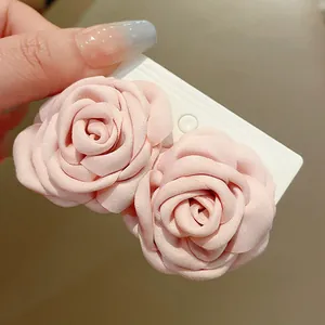 Detaillierte Nahaufnahme von weichen rosa Stoffrosen-Blumenzubehör auf einer weißen Karte