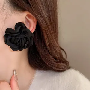 Detailaufnahme eines schwarzen Stoff-Ohrrings in Rosenform im Vintage-Stil an einem Model