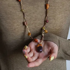 Vintage leather cord necklace with wooden beads and acorn pendant close-up view.