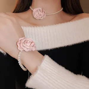 Nahaufnahme einer eleganten Perlenkette und eines passenden Armbands mit rosa Stoffrosen.