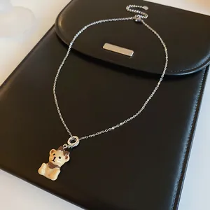 Elegant silver chain necklace featuring a cute cream-colored bear pendant with brown bow detail
