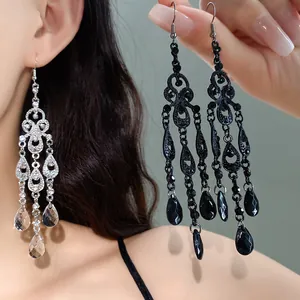 Detailed view of ornate hollow tassel chandelier earrings in silver and black colors
