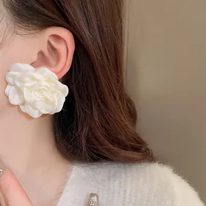Detail-Nahaufnahme eines eleganten weißen Stoffblumen-Ohrrings am Ohr eines Models