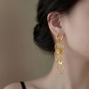 Close-up detail of elegant gold-toned hollow leaf tassel earrings worn on a model's ear.