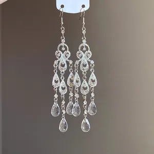 Detailed macro view of silver chandelier earrings with clear rhinestones and teardrop crystals