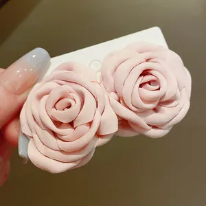 Nahaufnahme von zwei eleganten rosa Stoffrosen-Accessoires mit feiner Blütenstruktur.
